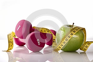 Apple dumbbells and tape measure on white glass table front