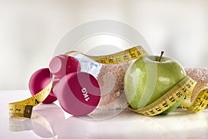 Apple dumbbells and tape measure on white table front gym