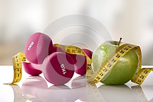 Apple dumbbells and tape on white glass table gym front