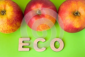 Apple Eco product or food. Three apples are on green background with text eco wooden letters. Example of sustainable environmental