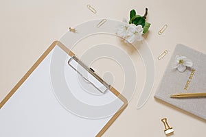 Apple flowers, notebook and tablet with paper mockup on a beige table. Feminine floral desktop