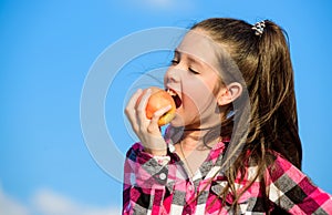 Apple fruit diet. Kid hold ripe apple sunny day. Kid girl with long hair eat apple blue sky background. Healthy