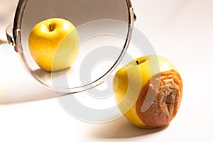 Apple in good condition looking at itself in the mirror while its back is rotten. Deception