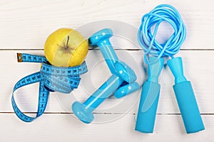 Apple in green color near barbells, centimeter and jump rope