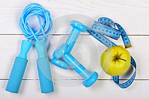 Apple in green color near barbells, centimeter and jump rope