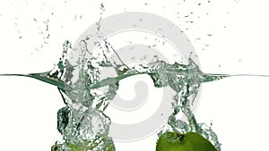 Apple halves plunging into water on white background