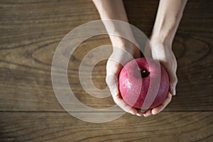 Apple in hands on a wooden table