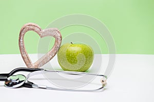 Apple, heart and stethoscope on horizontal green and white background