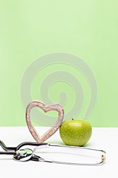 Apple, heart and stethoscope on vertical green and white background