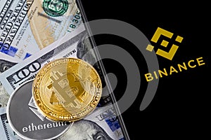 Apple iPhone and Binance logo and bitcoin, ethereum and dollars.