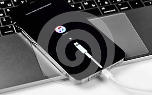 Apple iPhone with Lightning cable, iTunes logo on the screen