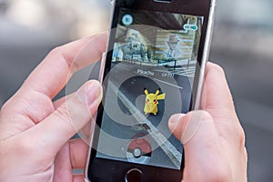 Apple iPhone5s with Pikachu from Pokemon Go application, hands of a teenager playing