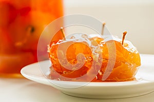 Apple jam in glass jar and on white plate