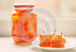 Apple jam in glass jar and on white plate