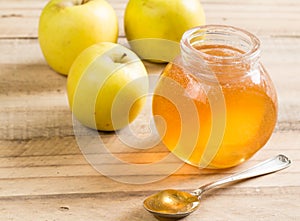 Apple jelly jar and spoon with granny smith apples on wooden tab