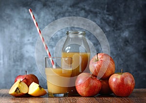 Apple juice in the glass with drinking straw - fruit around - gray background