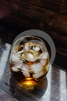 Apple juice with ice cubes in a glass cup is on the table