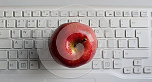 Apple Of Knowledge Concept. Perfect Ripe Apple Fruit On White Defocused Laptop Keyboard Top View