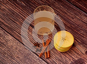 Apple liqueur with spices, homemade alcohol in a crystal bowl with cinnamon and anise on a wooden table