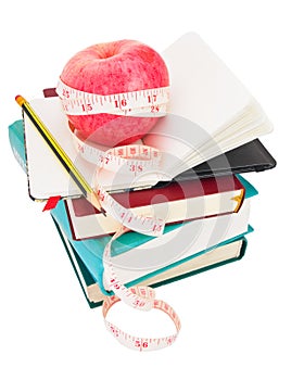 Apple with measure tape on big pile of books