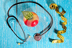 Apple, measuring tape and a stethoscope on the table, health concept.