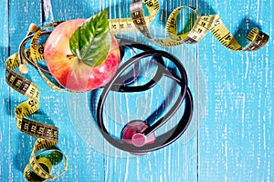 Apple, measuring tape and a stethoscope on the table, health concept