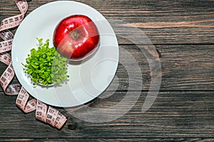 An apple with microgreen on an empty white plate with a tape measure to measure the figure. Diet and raw food concept.