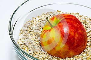 Apple on oat flakes in a glass bowl closeup