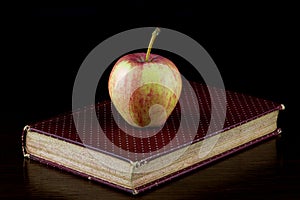 Apple on Old Book on a Polished Wooden Shelf