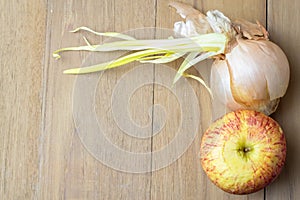 Apple and onion on wooden board