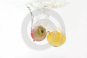 Apple and orange falling in water