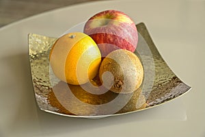 Apple, Orange and Kiwi fruit on a metal plate