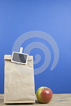 apple with paper bag on a wooden background. breakfast lunch bag