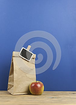 apple with paper bag on a wooden background. breakfast lunch bag