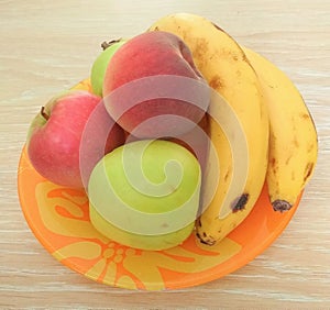 Apple, peach and banana on orange plate