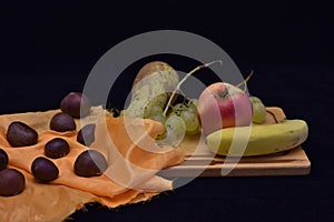 Chestnuts pear apple and banana grapes on the table photo