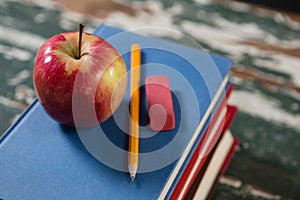Apple, pencil and eraser on stack of books