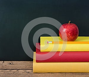 Apple and pencil on the stack of books