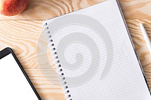 Apple, phone and notebook on a wooden background