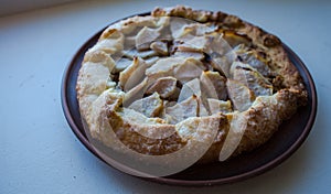 A apple pie on a clay plate on white background