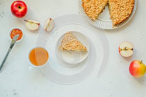 Apple pie piece and cup of tea, apples on white table background. Homemade classic frit pie. Copy space, top view