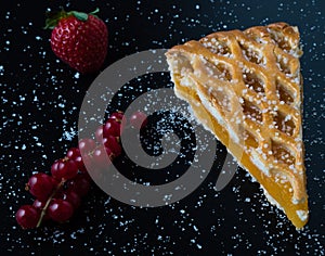 Apple pie slice on black table with currant and strawberry