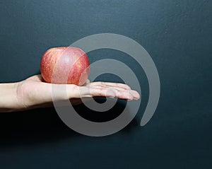 Apple is placed on supine palm with dark background