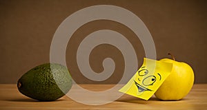 Apple with post-it note looking curiously at avocado