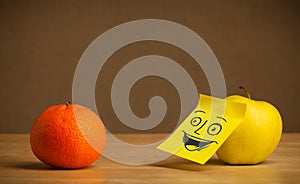 Apple with post-it note smiling at orange