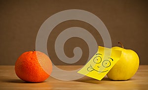 Apple with post-it note sticking out tongue to orange