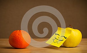 Apple with post-it note sticking out tongue to orange