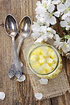 Apple preserve in glass jar standing on wooden table