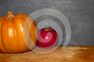 Apple and pumpkin on classroom table in front of blackboard