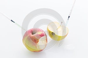 Apple with punched needles and syringes as a concept for modified food white background